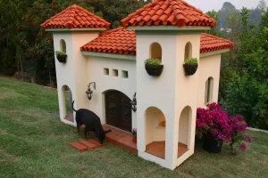 very fancy 2 story dog house with clay shingle roof & black dog in front